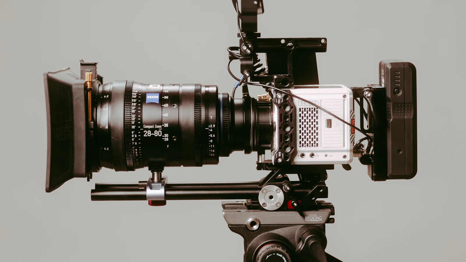 A professional cinema camera fitted with a Zeiss cine lens and matte box, mounted on a tripod in a studio